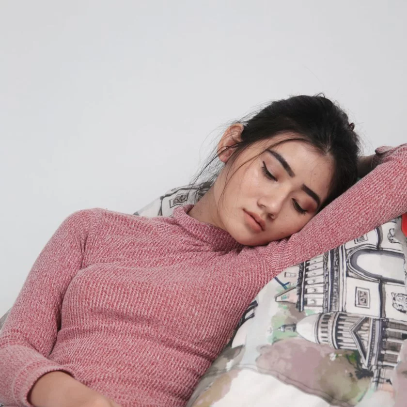 En kvinna sover, lutandes mot ett täcke