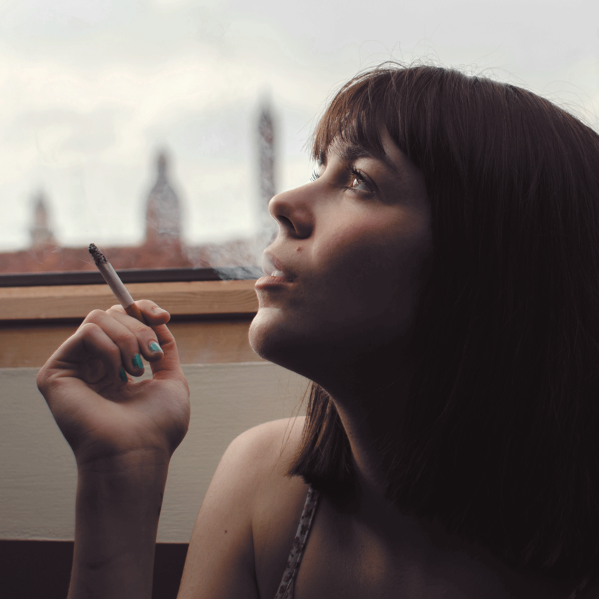 En kvinna som håller i en cigarett och blåser ut rök