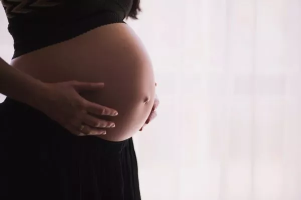 Kvinna håller händerna på sin gravida mage