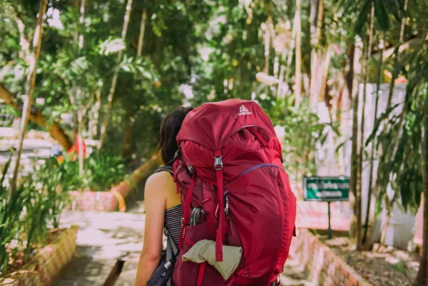 En kvinna bär en stor ryggsäck genom en skog