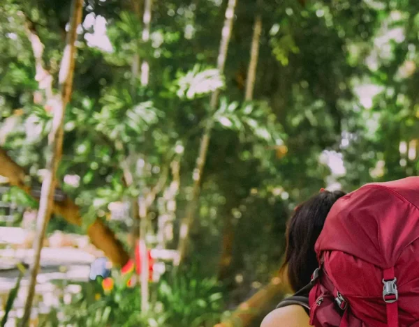 En kvinna bär en stor ryggsäck genom en skog