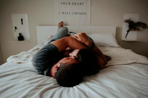 En man och en kvinna ligger på en säng och kramas