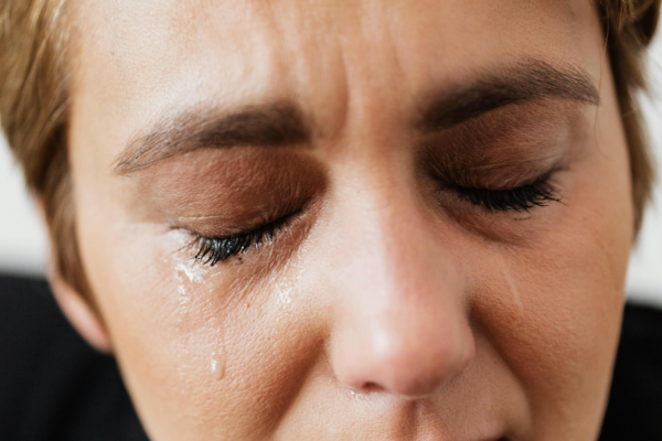 Närbild på en kvinnas ansikte med tårar som rinner från ögonen