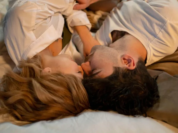 En kvinna och en man ligger nära varandra i en säng, panna mot panna