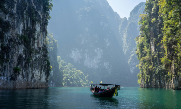 En thailändsk båt i en bukt med höga klippor